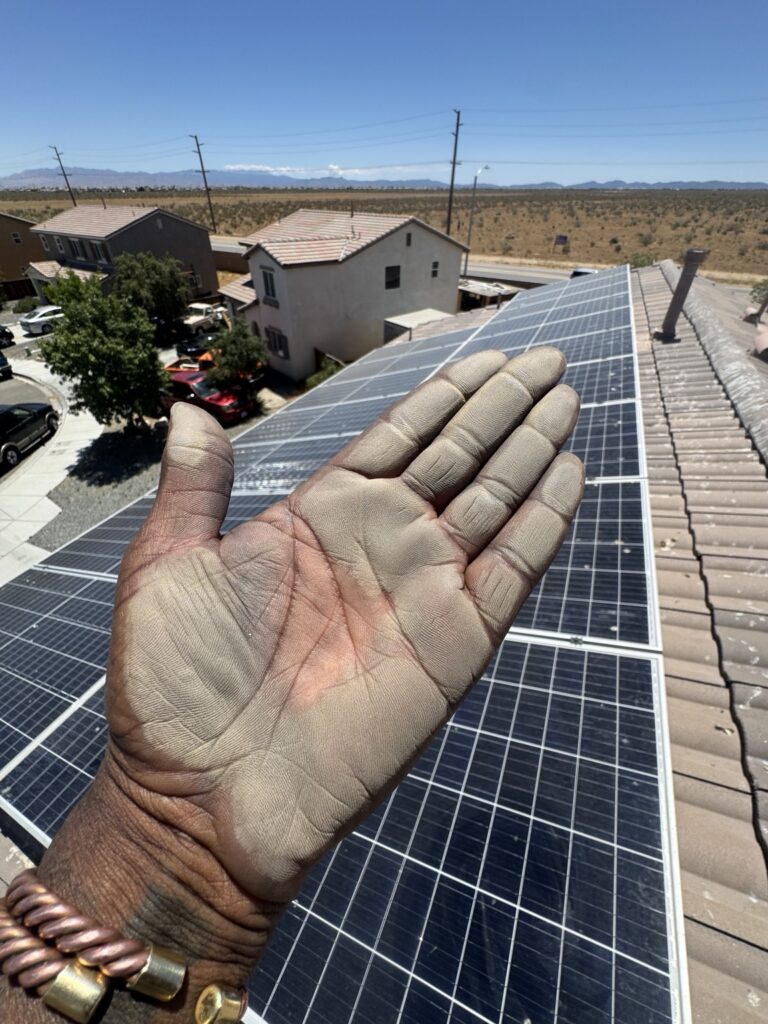 Dust on PJ’s hand beside a rooftop solar array