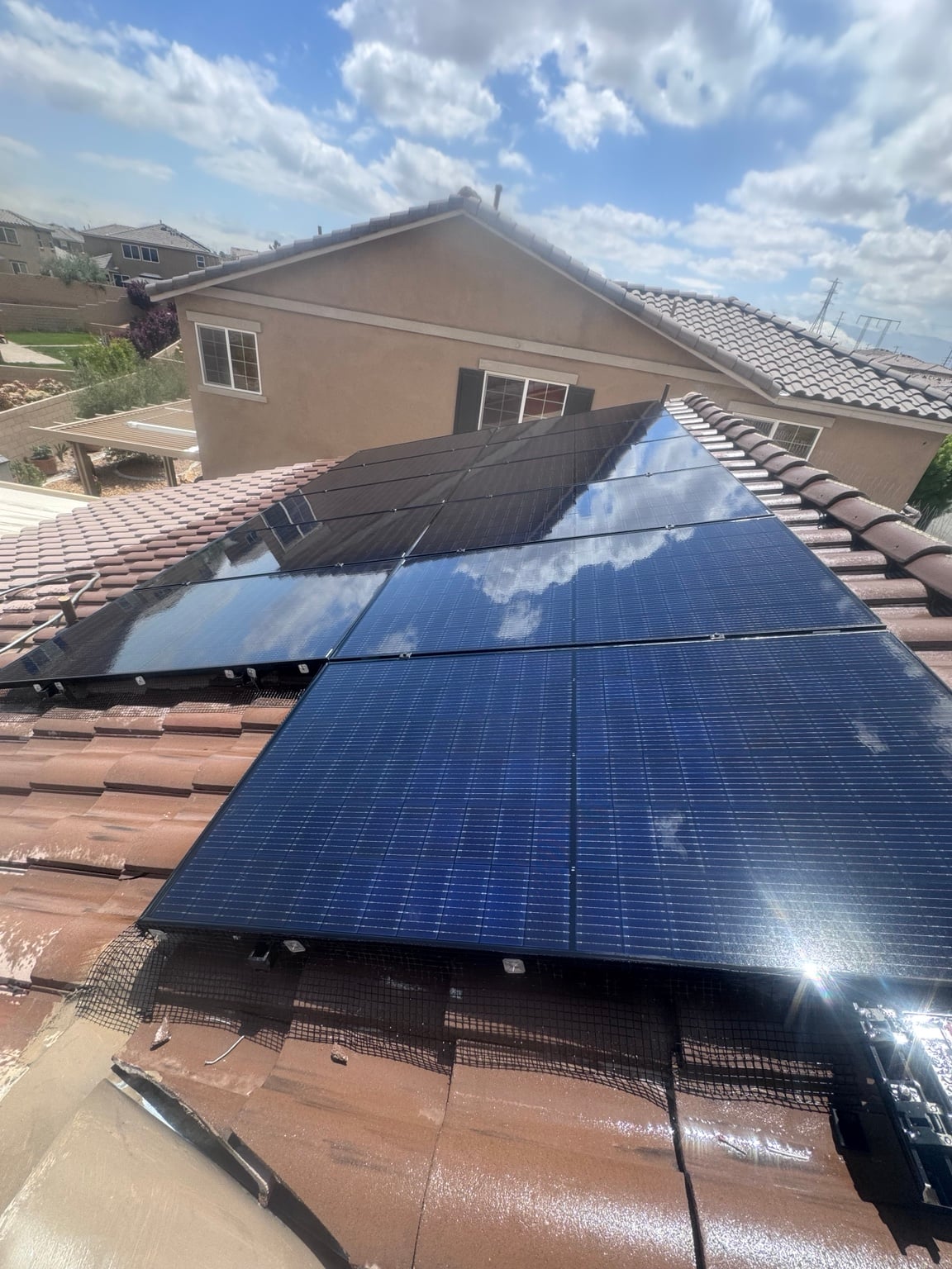 Freshly cleaned solar panels reflecting clouds on a tile roof